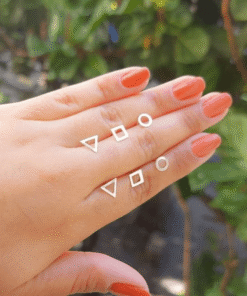 Mão feminina com unhas lilás mostrando brincos de prata