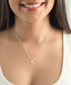 Modelo feminina de camiseta branca usando um colar Aviãozinho