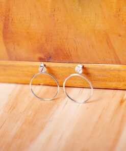 Foto do Brinco Circulo tamanho M apoiado em uma base de madeira rústica