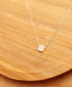 Foto do colar “Choker Madreperola”, acima de uma base de madeira rústica