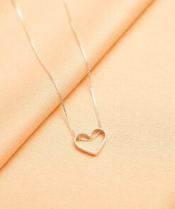 Foto do colar “Coração vazado”, acima de uma base de tecido