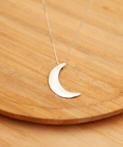 Foto do colar “Lua Lisa” tamanho G, acima de uma base de madeira rústica