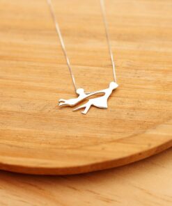 Foto do colar “Mãe e Filho”, acima de uma base de madeira rústica