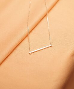 Foto do colar “Taquinho deitado”, acima de uma base de tecido