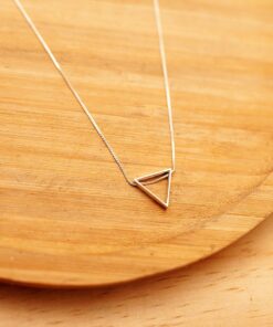 Foto do Colar Triangulo 3D acima de uma base de madeira rústica