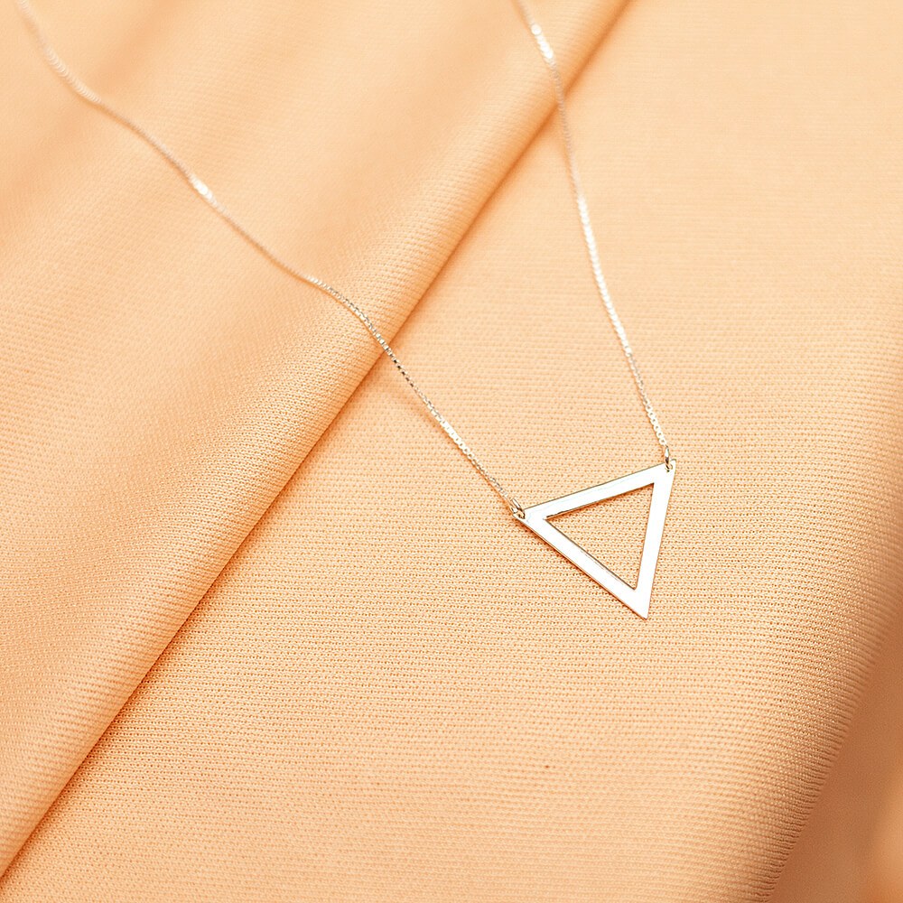 Foto do colar “Triangulo Vazado”, acima de uma base de tecido