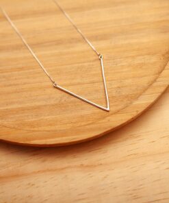 Foto do Colar V tamanho G, acima de uma base de madeira rústica