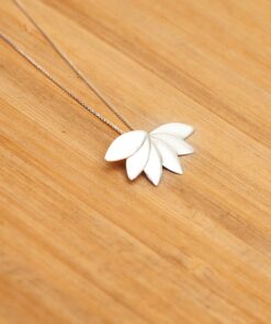 Foto do colar “Flor de lótus”, acima de uma base de madeira rústica