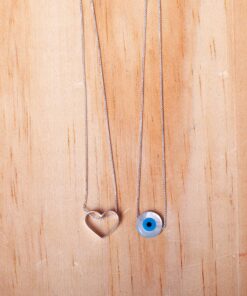 Foto do Escapulário “Coração e Olho Grego”, acima de uma base de madeira rústica