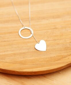 Foto do colar “Gravatinha Circulo e Coração”, acima de uma base de madeira rústica