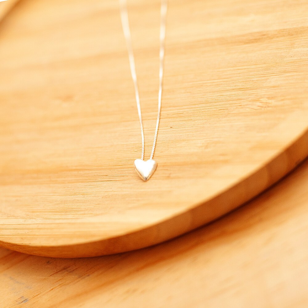 colar coração de prata 925 em um prato de madeira