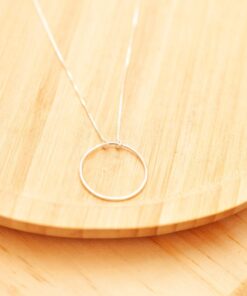 Colar circulo vazado sobre um prato de madeira