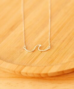 colar onda de prata 925 sobre um prato de madeira