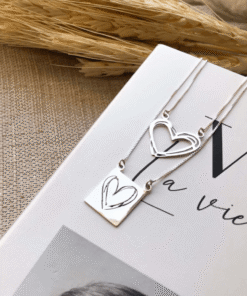 Escapulario Corações em prata 925 em cima de um livro