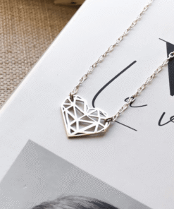 Colar Coração Recortes em prata 925 em cima de um livro