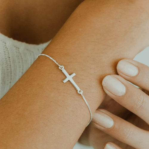 Pulseira cruz mini de prata 925 em braço feminino