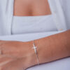 Pulseira cruz mini de prata 925 em braço feminino