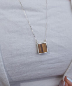 Modelo feminina usando Escapulario Olho de Tigre e Onix Quadrado de prata 925